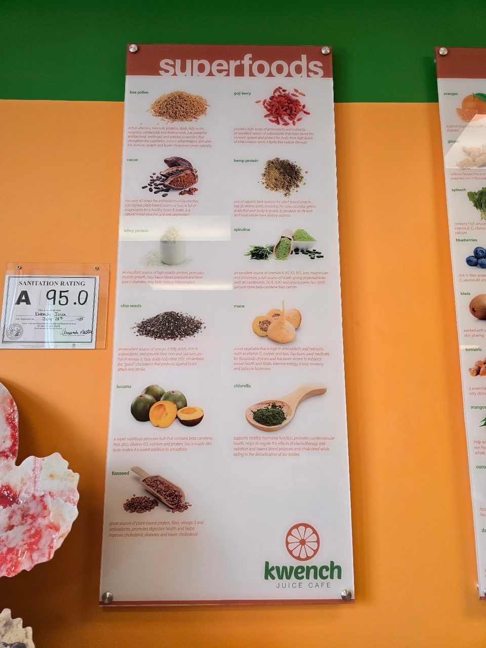 A Kwench Juice Cafe "Superfoods" informational poster with a 95.0 sanitation rating certificate.